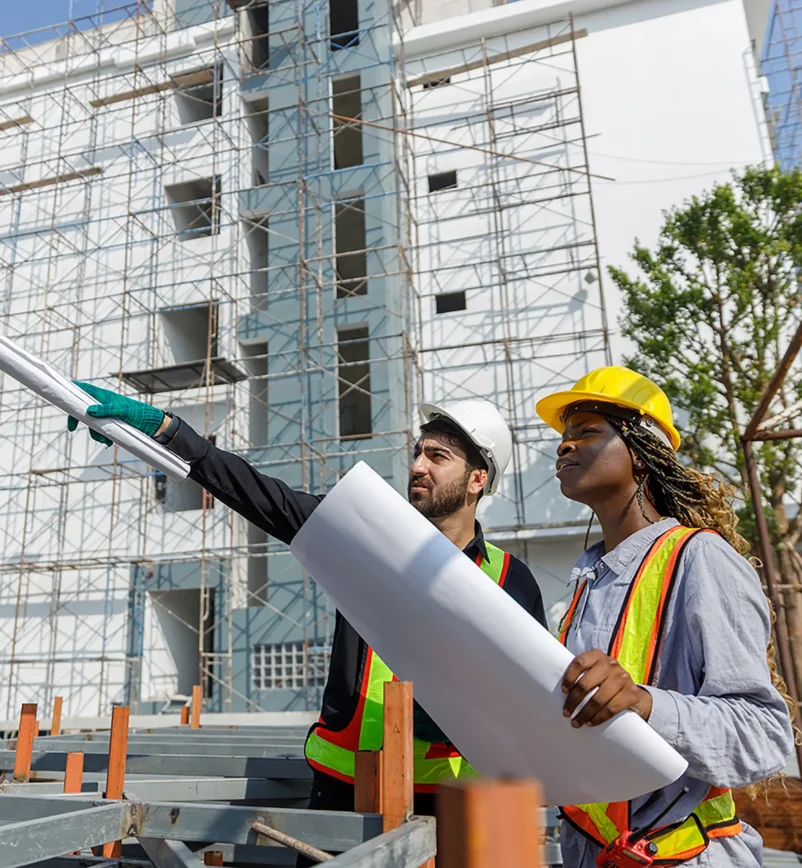 Construction civil engineer man and woman African American checking quality of work in construction site. Team of various nationalities working inspecting infrastructure building progress.